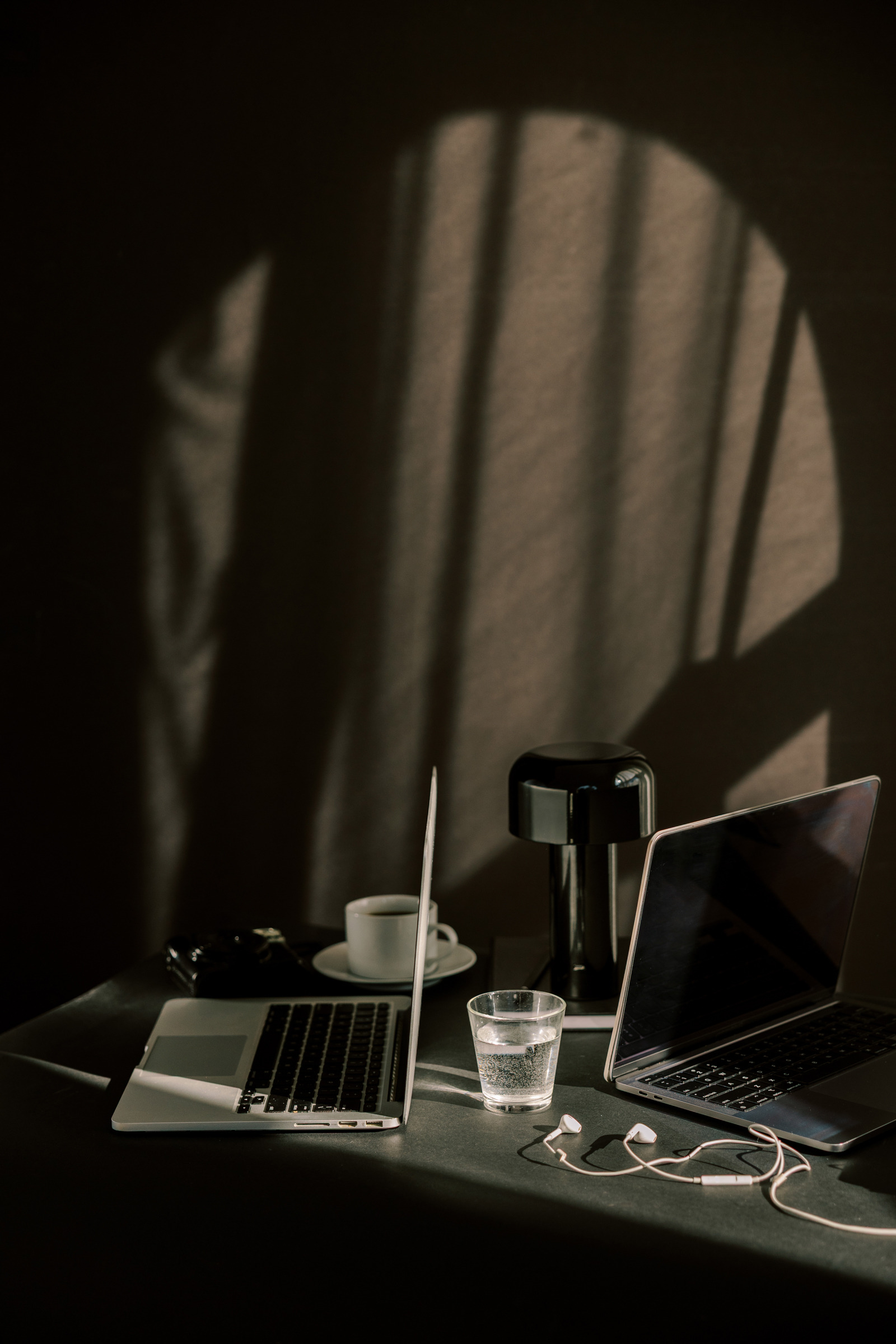 Two open laptops facing each other on a dark desk, illustrating different AI tools and business workflows.